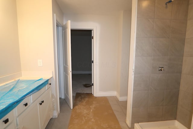 bathroom with a tile shower and vanity