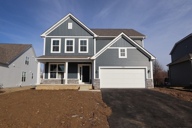 craftsman house with a porch, stone siding, driveway, and board and batten siding