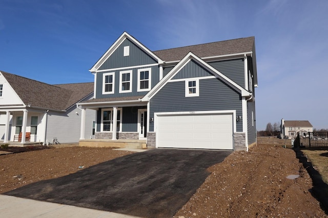 craftsman-style home featuring a porch, board and batten siding, a garage, stone siding, and driveway