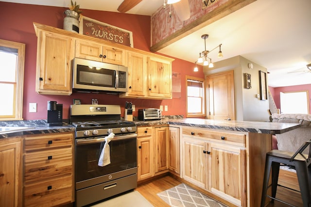 kitchen featuring kitchen peninsula, light wood-type flooring, a breakfast bar, stainless steel appliances, and ceiling fan