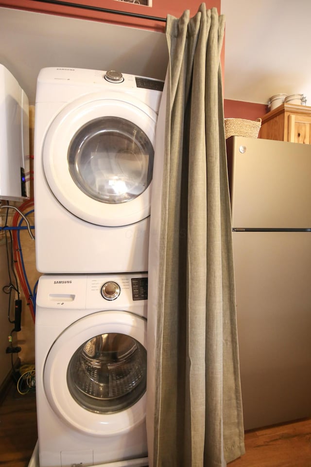 laundry room with wood-type flooring and stacked washing maching and dryer