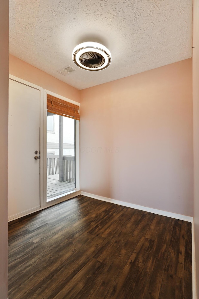 unfurnished room with a textured ceiling and dark wood-type flooring