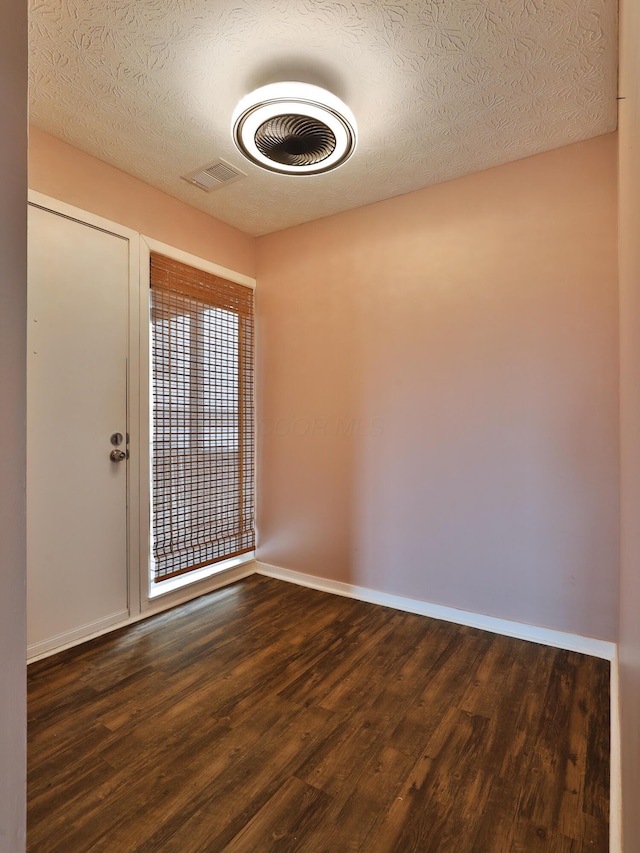 empty room featuring a textured ceiling and dark wood-type flooring