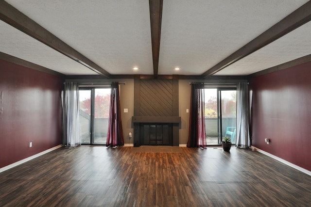 unfurnished living room featuring plenty of natural light, beamed ceiling, and a textured ceiling