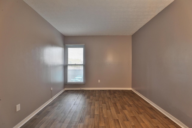 unfurnished room featuring a textured ceiling and dark hardwood / wood-style floors