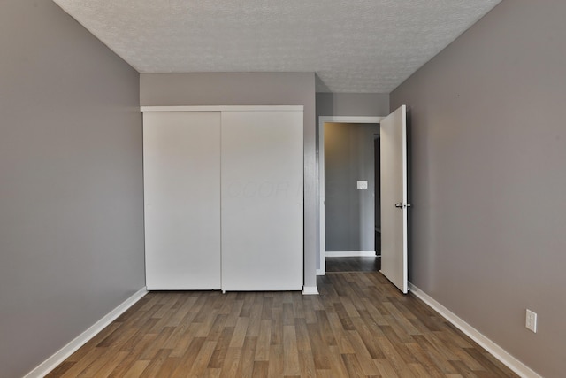 unfurnished bedroom featuring a closet, hardwood / wood-style floors, and a textured ceiling