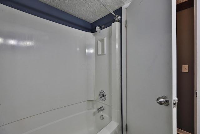 bathroom with  shower combination and a textured ceiling