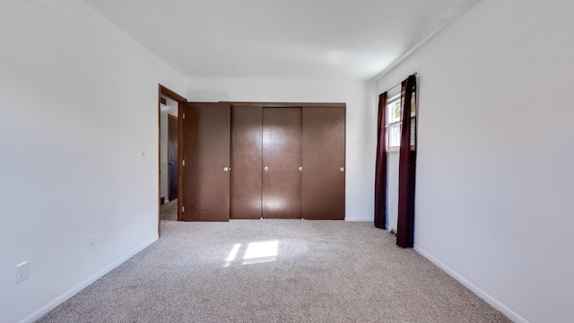 unfurnished bedroom with a closet and light colored carpet