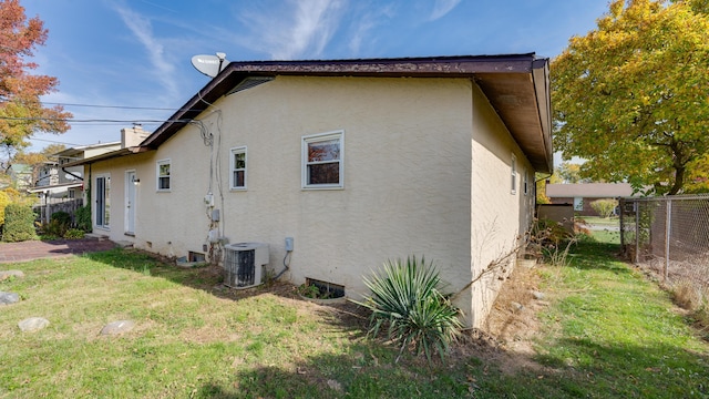 view of side of property featuring a lawn and cooling unit