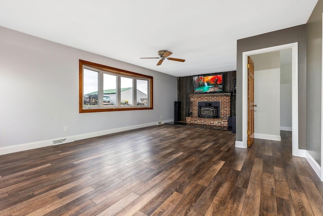 unfurnished living room with a wood stove, ceiling fan, and dark hardwood / wood-style flooring