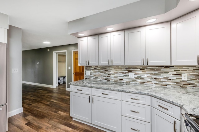 kitchen with backsplash, light stone counters, stainless steel stove, white cabinets, and dark hardwood / wood-style floors