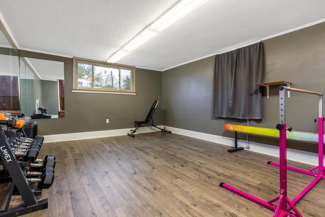 workout area featuring wood-type flooring, a textured ceiling, and ornamental molding