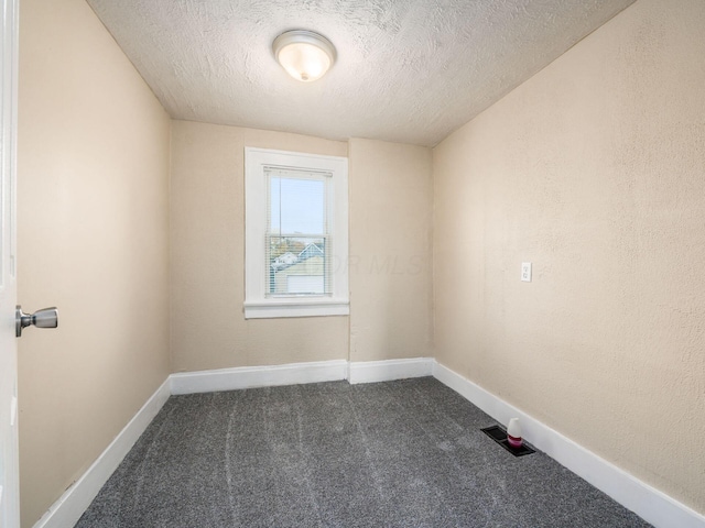 unfurnished room with dark carpet and a textured ceiling