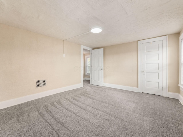 spare room featuring carpet flooring and a textured ceiling