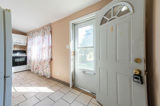 doorway featuring light tile patterned flooring and lofted ceiling