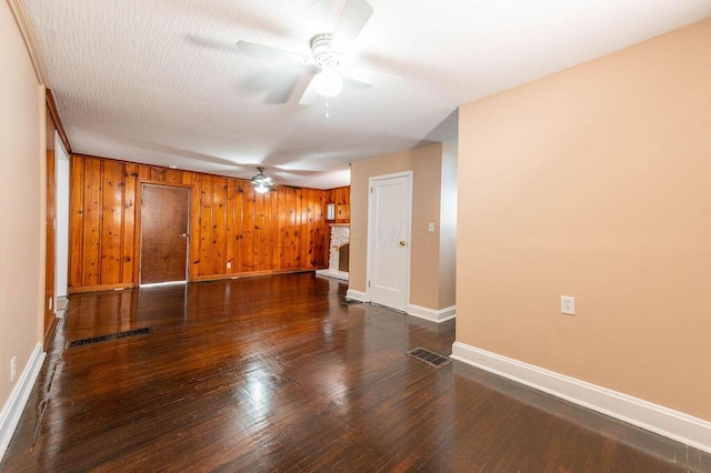 unfurnished room featuring dark hardwood / wood-style floors, ceiling fan, and wood walls