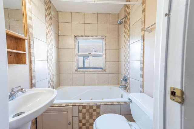 full bathroom featuring tiled shower / bath combo, toilet, sink, and tile walls