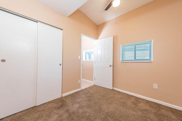 unfurnished bedroom featuring ceiling fan, a closet, light carpet, and lofted ceiling