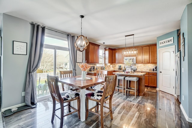 dining area with dark hardwood / wood-style floors and an inviting chandelier