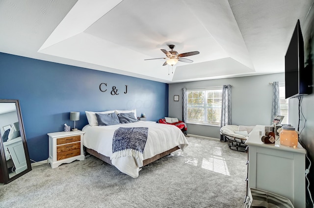 bedroom featuring light carpet, a raised ceiling, and ceiling fan