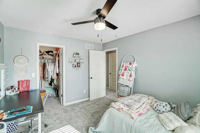 carpeted bedroom featuring a walk in closet, a closet, and ceiling fan