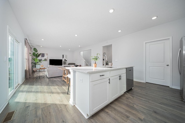 kitchen with white cabinets, hardwood / wood-style flooring, a kitchen island with sink, and sink