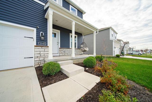 doorway to property featuring a lawn, a garage, and covered porch