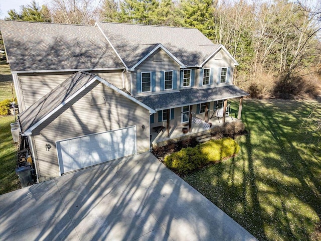 view of front of home with a shingled roof, a front yard, covered porch, driveway, and an attached garage