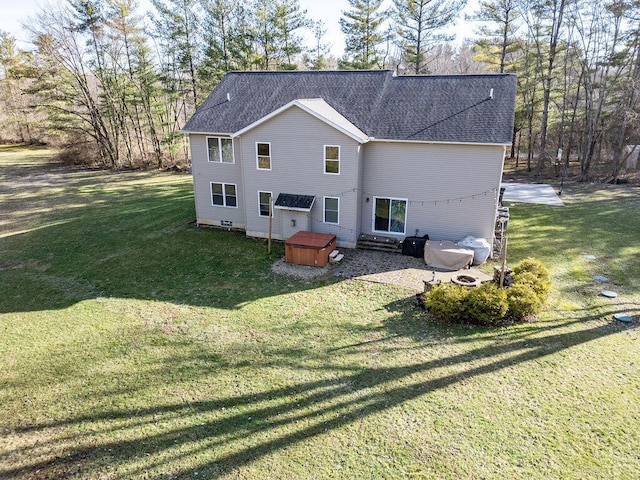 back of property featuring a lawn and a shingled roof