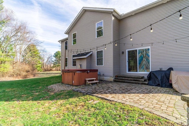 back of property with a patio area, a lawn, entry steps, and a hot tub