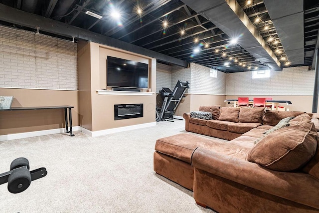 living area with a glass covered fireplace, carpet flooring, baseboards, and brick wall