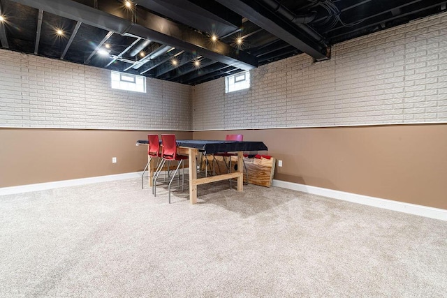 interior space featuring carpet flooring, brick wall, and baseboards