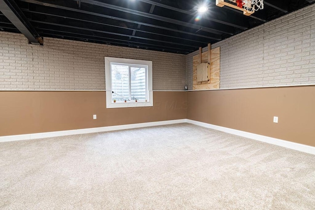 basement featuring baseboards, carpet floors, and brick wall