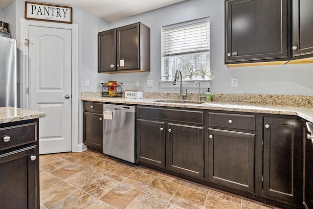 kitchen featuring a sink, stainless steel appliances, light stone counters, and dark brown cabinets