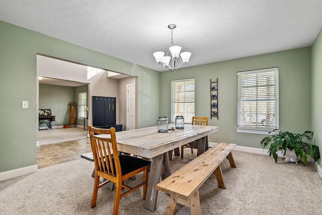 dining room with a textured ceiling, baseboards, a notable chandelier, and carpet