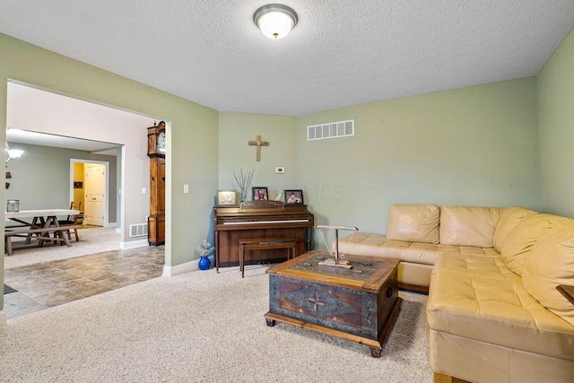 carpeted living room with visible vents, baseboards, and a textured ceiling