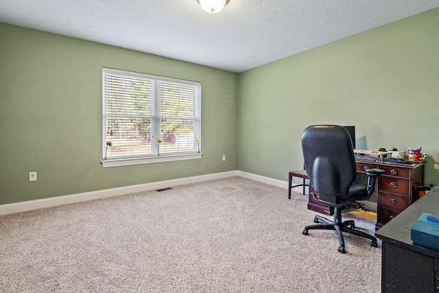 carpeted office featuring visible vents, baseboards, and a textured ceiling