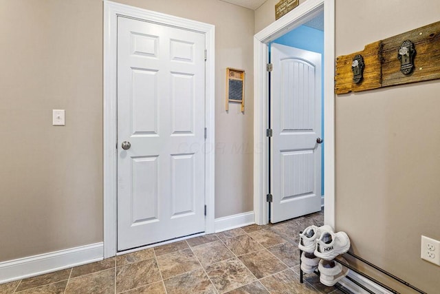 foyer with baseboards and stone finish flooring