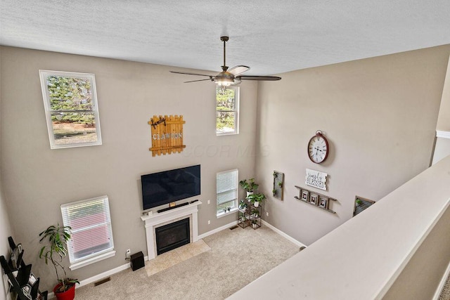 carpeted living room featuring a fireplace with flush hearth, baseboards, visible vents, and a textured ceiling