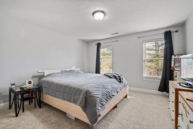 bedroom with light carpet, visible vents, a textured ceiling, and baseboards