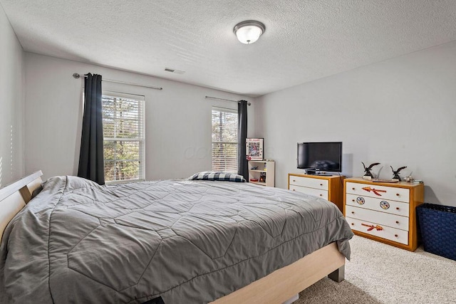 carpeted bedroom with visible vents and a textured ceiling