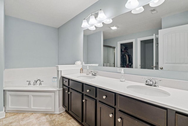 full bathroom with double vanity, visible vents, a garden tub, and a sink