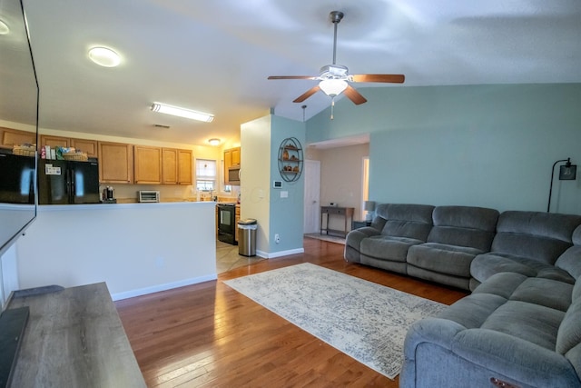 living room featuring light hardwood / wood-style flooring, ceiling fan, and vaulted ceiling