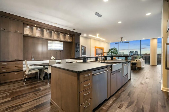 kitchen featuring dishwasher, sink, dark wood-type flooring, an island with sink, and decorative light fixtures