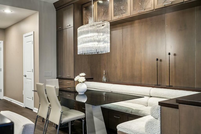 bar featuring dark hardwood / wood-style flooring, light stone counters, and dark brown cabinets