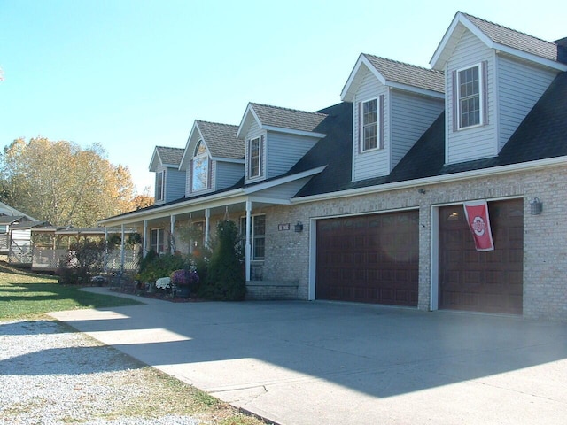 cape cod-style house featuring a porch and a garage