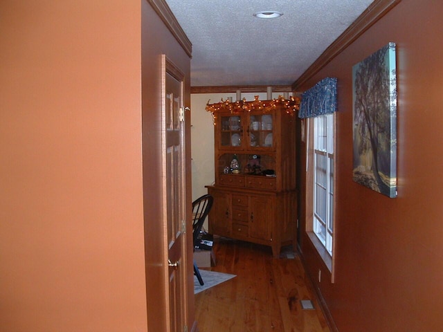 hall featuring dark wood-type flooring, a textured ceiling, and ornamental molding