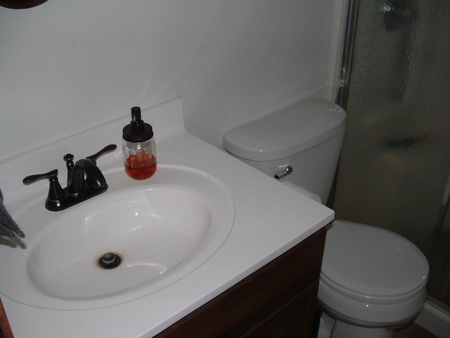 bathroom featuring an enclosed shower, vanity, and toilet