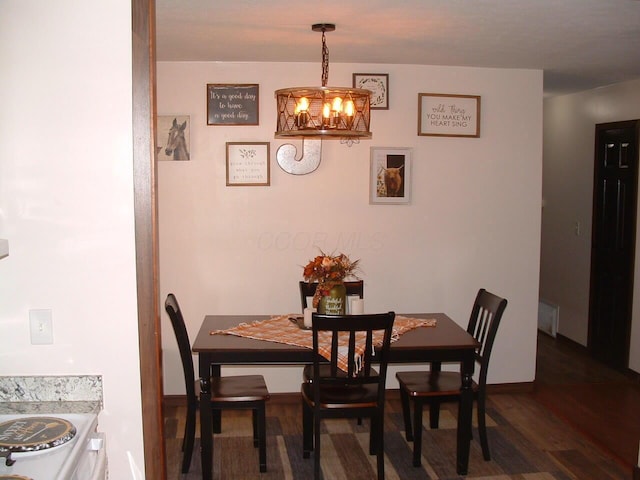 dining area featuring dark hardwood / wood-style flooring and an inviting chandelier