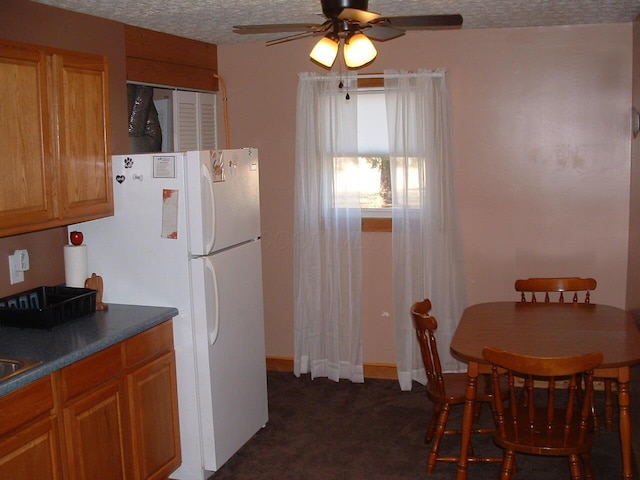 kitchen featuring ceiling fan, white fridge, a textured ceiling, and dark colored carpet